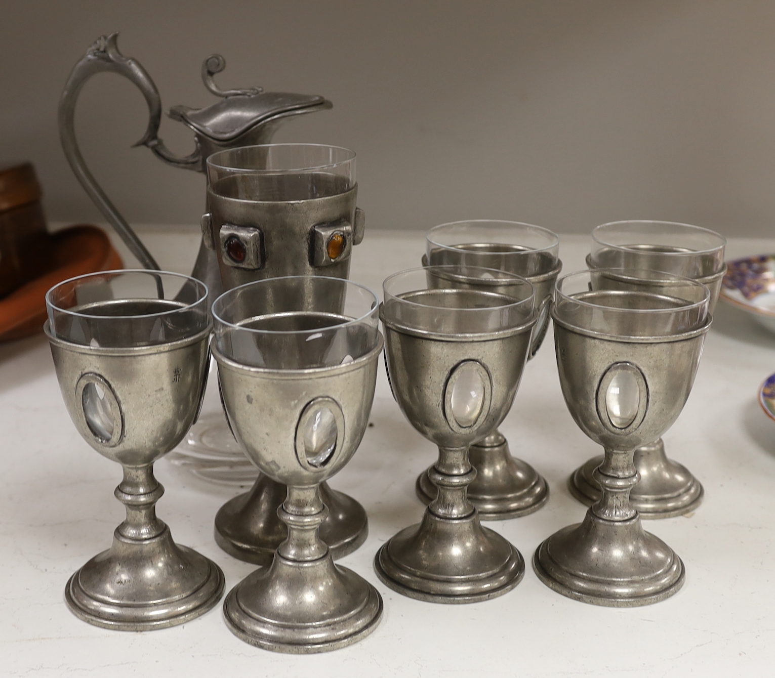 A set of six 20th century French pewter and glass goblets, together with larger example inset with cabochon stones and a pewter mounted glass claret jug, the largest 28cm high
